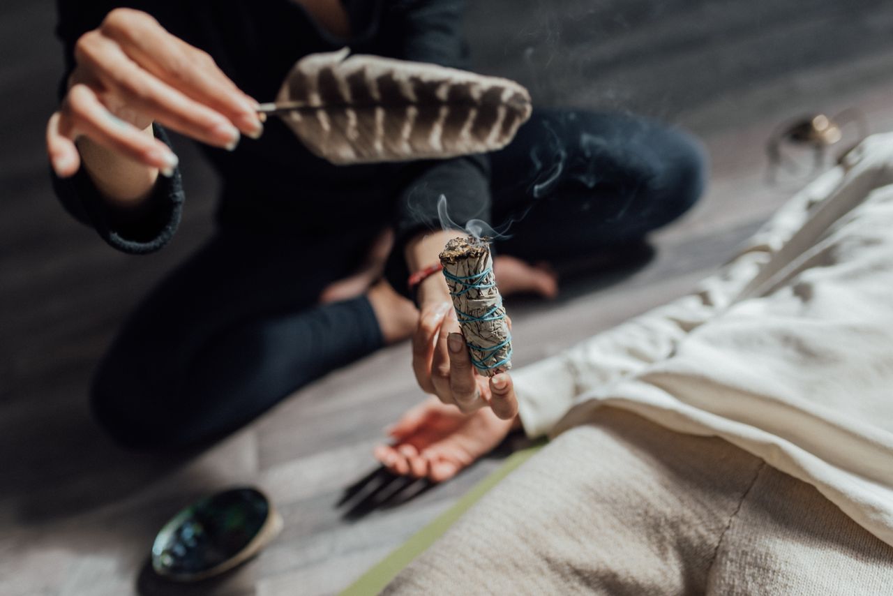 our-story Close-up of a cleansing ritual using sage and a feather, depicting wellness and meditation.